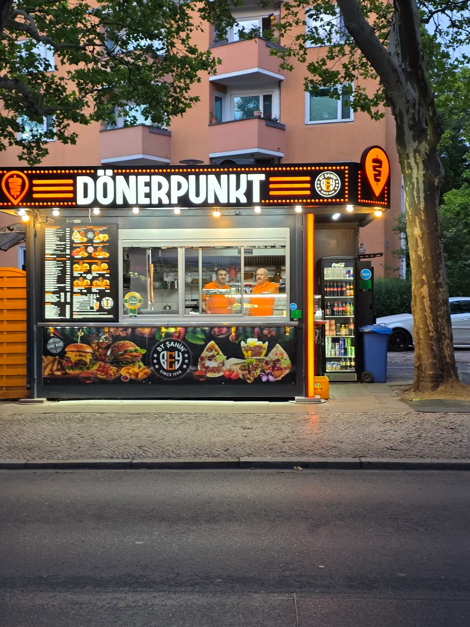 Mitarbeiter von Dönerpunkt freundlich lächelnd hinter der Verkaufstheke am Abend
